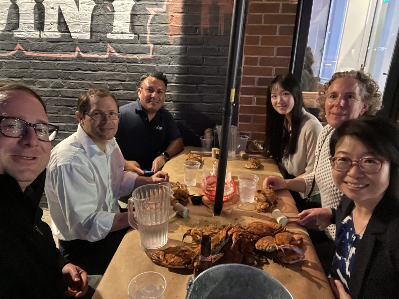 Lab members and friends around a table piled with steamed crabs