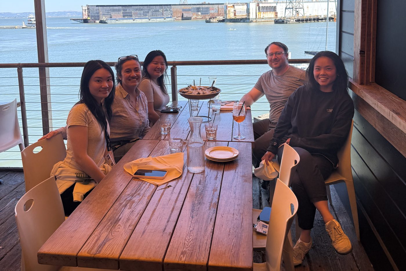 Lab members around a table on a covered waterfront deck
